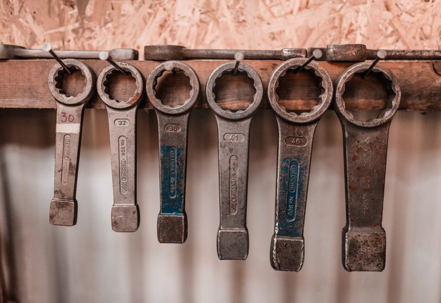A row of worn spanners hanging on a board