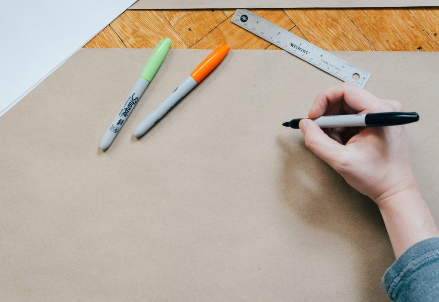 A hand drawing a plan with a ruler and markers